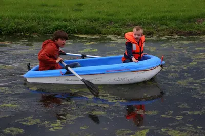 two boys are in a boat on the water at Boerderij Hazenveld in Kockengen
