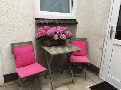 a table with pink chairs and a basket of flowers at Romana in Zandvoort