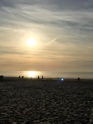 a group of people walking on the beach at sunset at Romana in Zandvoort