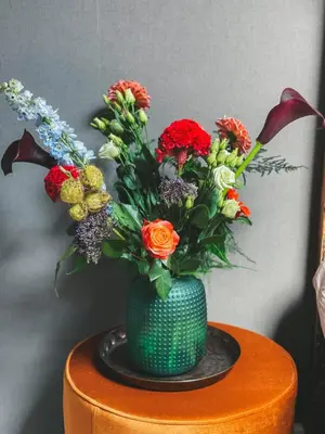 a green vase filled with flowers on a table at B&B Landslake I in Landsmeer
