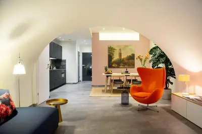 a living room with an orange chair and a table at LOFT 188 Luxury Apartment Hotel in Utrecht