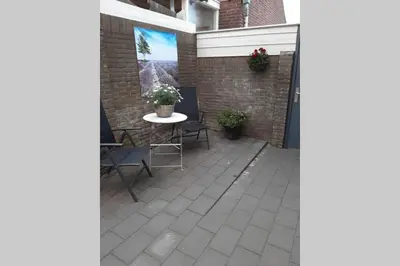 a patio with a table and chairs and a brick wall at Zomerhuis Strand 28 in Egmond aan Zee