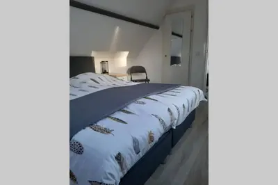 a large bed in a room with a chair at Zomerhuis Strand 28 in Egmond aan Zee