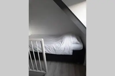 a small bed in a small room next to a staircase at Zomerhuis Strand 28 in Egmond aan Zee