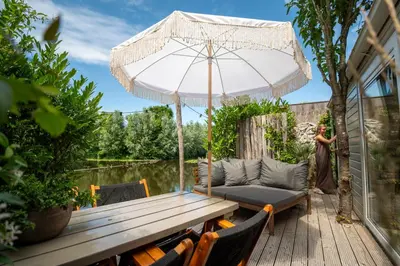 a woman standing on a deck with a table and an umbrella at LODGE & LOFT in Sassenheim