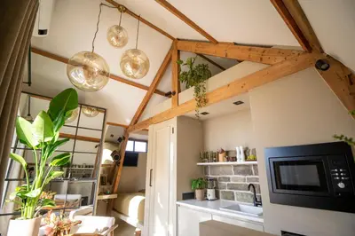 a room with wooden beams and a living room with a tv at LODGE & LOFT in Sassenheim