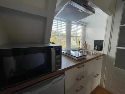 a kitchen with a microwave and a sink at Coconut Beach apartments in Zandvoort