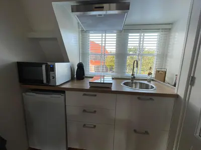 a kitchen with a sink and a microwave and a window at Coconut Beach apartments in Zandvoort