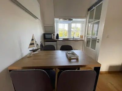 a dining room table with chairs and a laptop on it at Coconut Beach apartments in Zandvoort