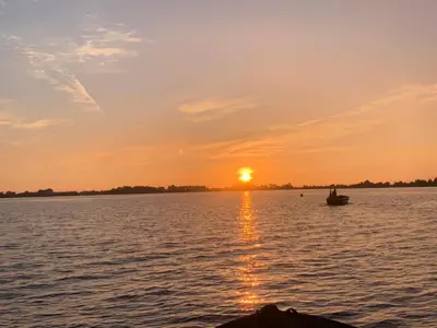 a boat on a lake with the sun setting at Water Villa Minaro Vinkeveen in Vinkeveen