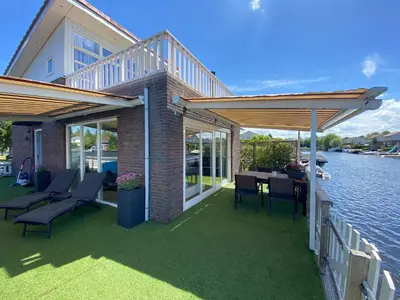 a patio with chairs and a table on the water at Water Villa Minaro Vinkeveen in Vinkeveen