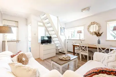 a living room with a white couch and a staircase at Küstenwind in Zandvoort