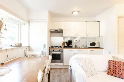 a kitchen with white cabinets and a wooden table at Küstenwind in Zandvoort
