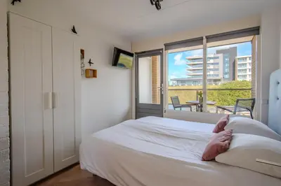 a bedroom with a white bed and a balcony at Perfect Stay Holiday, Moment at Sea in Egmond aan Zee