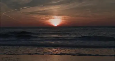 a sunset over the ocean with the sun setting at Perfect Stay Holiday, Moment at Sea in Egmond aan Zee