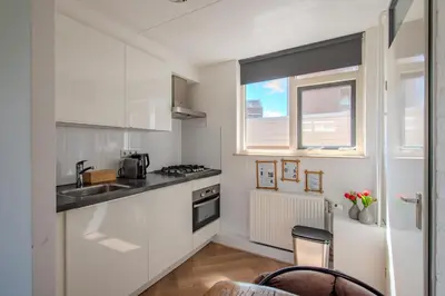 a kitchen with white cabinets and a sink and a window at Perfect Stay Holiday, Moment at Sea in Egmond aan Zee