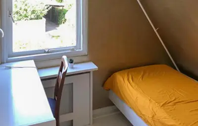 a bedroom with a bed and a desk and a window at Paradis in Bergen