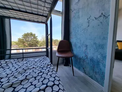 a bedroom with a bed and a chair and a window at De Schelp 73 the perfect place! in Zandvoort