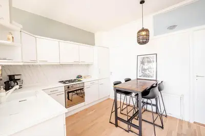 a kitchen with white cabinets and a wooden table at Amsterdam Beach Apartment 1, Private Garden in Zandvoort