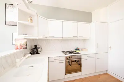 a white kitchen with white cabinets and a stove at Amsterdam Beach Apartment 1, Private Garden in Zandvoort