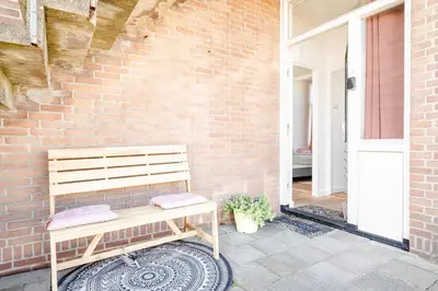 a wooden bench sitting next to a brick wall at Amsterdam Beach Apartment 1, Private Garden in Zandvoort