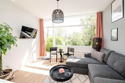 a living room with a couch and a large window at Amsterdam Beach Apartment 1, Private Garden in Zandvoort