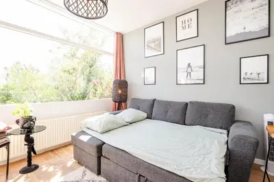 a living room with a couch and a window at Amsterdam Beach Apartment 1, Private Garden in Zandvoort