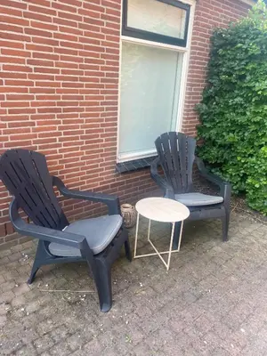 two chairs and a table in front of a brick building at 99 Lifestyle Suite in Zwaag
