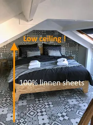 a bedroom with a bed with a low ceiling at Houseboat apartment with water terrace, free bikes & fast wifi in Amsterdam