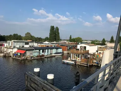 a marina with houses and boats on the water at Houseboat apartment with water terrace, free bikes & fast wifi in Amsterdam