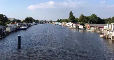 a river with houses and buildings on the sides at Houseboat apartment with water terrace, free bikes & fast wifi in Amsterdam