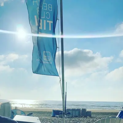 a blue flag on a beach with the ocean at ‘T Vissershuisje in Zandvoort