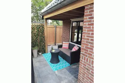 a backyard patio with a black couch and a table at Zomerhuis Adriana in Egmond aan Zee