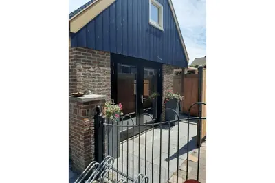 a blue house with a black fence and a building at Zomerhuis Adriana in Egmond aan Zee