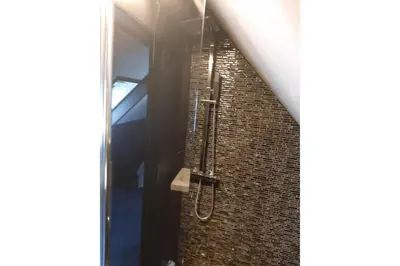 a shower in a bathroom with a brick wall at Zomerhuis Adriana in Egmond aan Zee
