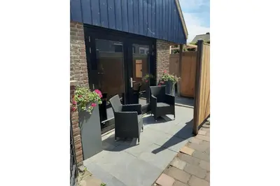 a patio with chairs and flowers on a building at Zomerhuis Adriana in Egmond aan Zee