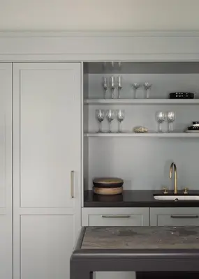 a kitchen with white cabinets and a sink and wine glasses at Boutique Hotel Benedict Noordwijk in Noordwijk aan Zee