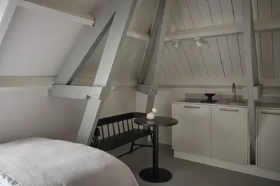 a bedroom with a bed and a table and a kitchen at Boutique Hotel Benedict Noordwijk in Noordwijk aan Zee