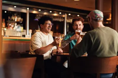 three men sitting at a bar drinking beer at DFDS Mini Cruise Amsterdam - Newcastle - Amsterdam in IJmuiden