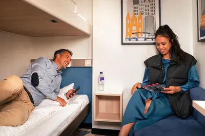 a man and a woman sitting on a bed at DFDS Mini Cruise Amsterdam - Newcastle - Amsterdam in IJmuiden