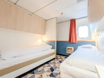 two beds in a small room with a window at DFDS Mini Cruise Amsterdam - Newcastle - Amsterdam in IJmuiden