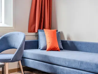 a blue couch with an orange pillow next to a chair at DFDS Mini Cruise Amsterdam - Newcastle - Amsterdam in IJmuiden