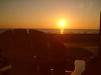 a chair on the beach watching the sunset at Luxe Strandhuisje op het strand van Wijk aan Zee met wifi in Wijk aan Zee