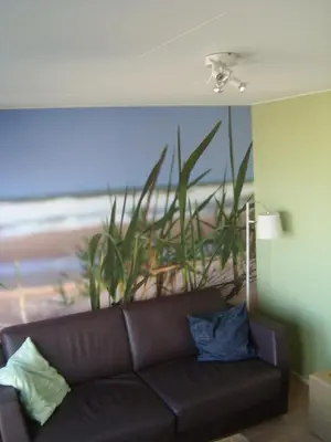 a couch in a living room with a painting of the beach at Luxe Strandhuisje op het strand van Wijk aan Zee met wifi in Wijk aan Zee