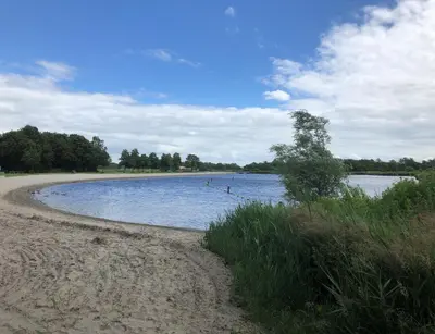 a large body of water with trees and a beach at B&B Twiske Zuid, Amsterdam free parking in Amsterdam