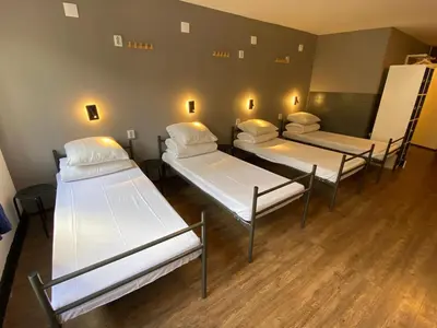a group of beds in a room with wood floors at Xplore Hostel Amsterdam in Amsterdam