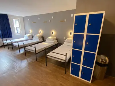 a room with four beds and a mirror at Xplore Hostel Amsterdam in Amsterdam