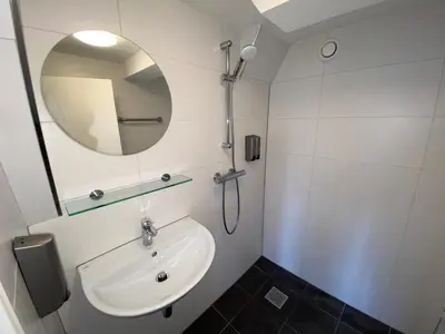 a white bathroom with a sink and a mirror at Xplore Hostel Amsterdam in Amsterdam