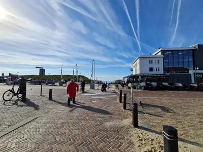 a woman in a red coat walking down a street at Ferienhaus Abenteuer in Egmond aan Zee