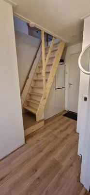 an empty room with stairs in a room with a kitchen at Ferienhaus Abenteuer in Egmond aan Zee